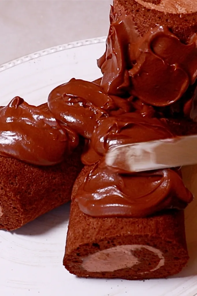spreading ganache onto chocolate roll cake to make buche de noel