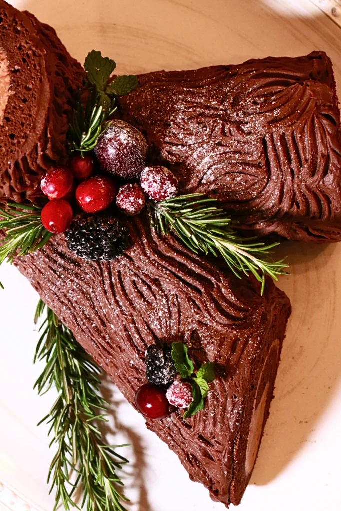 classic homemade yule log cake decorated with herbs and fresh fruits