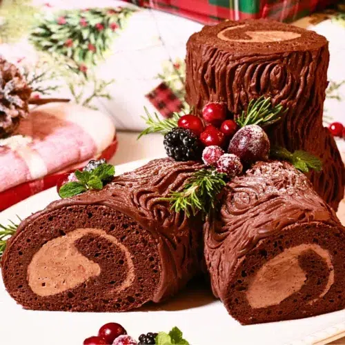 classic buche de noel decorated with herbs and fresh fruits