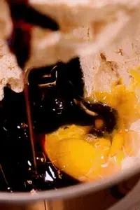 adding egg, molasses, and vanilla to butter and sugar