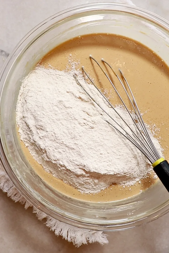 adding flour to the peanut butter mixture to make muffins